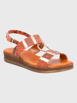 Sandalia de plataforma baja con tiras estampadas en animal print de serpiente en tonos naranja y negro. Presenta detalles de apliques metálicos dorados, una argolla central decorativa y cierre mediante hebilla lateral.