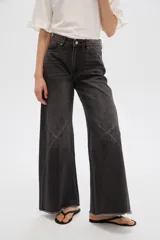 Pantalón jean gris de tiro alto, corte ancho (wide leg) con diseño de paneles tipo patchwork y terminación desmechada en el dobladillo.