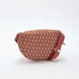 Riñonera de diseño acolchado con estampado de pequeñas hojas blancas sobre fondo color terracota. Cuenta con cierre metálico dorado y correa ajustable del mismo tono.