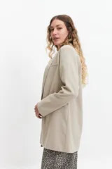 Blazer color beige estilo lino, de corte recto y largo a la cadera.