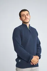 Sweater de tejido de punto acanalado en color negro, con cuello alto y cierre frontal parcial. Cuenta con mangas largas y un pequeño logo bordado en el ruedo.