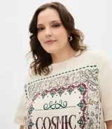Remera de algodón color beige con cuello redondo, mangas cortas y corte holgado. Presenta un estampado frontal con la frase 'Cosmic Dream' rodeada por un diseño de estilo bandana.