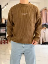 Sweater de punto color marrón, de manga larga, con textura acanalada y texto bordado en la espalda.