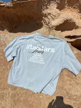 Remera celeste de corte recto con estampado en la espalda que incluye el texto "Itta Stars Tour" y una lista de ciudades: Ibiza, Madrid, Andorra, Barcelona y Formentera.