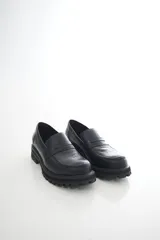 Mocasines de cuero vacuno en color negro, con suela track gruesa y diseño de dos texturas que combina piel lisa y empeine grabado con relieve.