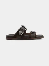 Sandalias de cuero marrón chocolate, con dos tiras anchas en el empeine provistas de grandes hebillas y detalles metálicos plateados en estilo western.