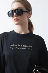 Remera negra de manga corta con bordado en color beige que dice "dolce far niente" y "The sweetness of doing nothing". Tiene un calce relajado.