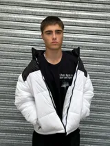 Campera puffer blanca con canesú y cuello alto negros, cierre frontal con cremallera y bolsillos laterales con cierre.