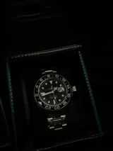 Reloj de pulsera con diseño clásico, caja de acero inoxidable de 40mm y malla de eslabones metálicos. Presenta esfera negra con indicadores luminiscentes y bisel giratorio graduado.