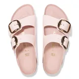 Sandalias Birkenstock modelo Arizona Big Buckle, de color rosado claro con dos tiras anchas ajustables mediante hebillas metálicas grandes de color dorado. Presentan plantilla anatómica forrada en cuero, entresuela de corcho y suela de goma estriada negra.