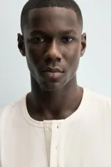 Camiseta blanca de manga corta con cuello redondo y tapeta de botones frontal (cuello panadero o henley).