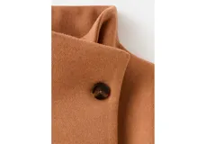 Abrigo corto de paño en color camel, con cuello alto, cierre frontal de botones y bolsillos laterales con solapa. Presenta un diseño de corte recto y estructura holgada.