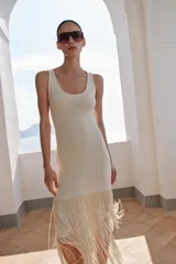 Vestido midi de escote redondo y sin mangas, confeccionado en tejido con textura. Presenta un diseño recto con bajo acabado en capas de flecos largos al tono.