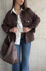 Sobrecamisa de gabardina color marrón chocolate, de corte holgado, con bolsillos con solapa en el pecho, mangas largas y cierre frontal de botones metálicos.