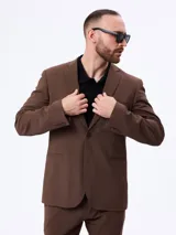 Traje slim color marrón de dos piezas, compuesto por un saco entallado de dos botones y un pantalón de corte recto. Confeccionado en mezcla de lana y poliéster.