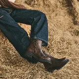 Bota corta de cuero vacuno marrón, con suela gruesa de goma y plataforma tractorada negra, punta redonda y elástico lateral.