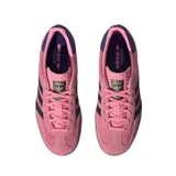 Zapatillas Adidas Gazelle Indoor color rosa con las tres rayas laterales en negro y detalles en azul marino en el talón. Suela de goma color caramelo.