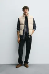 Chaleco acolchado de corte regular, color negro, con cuello alto, cierre frontal con cremallera y bolsillos laterales de vivo.