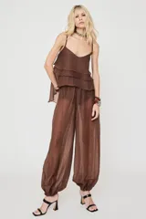 Pantalón marrón de corte ancho y estilo balloon, confeccionado en tejido translúcido con textura sutil y puños fruncidos en los tobillos.