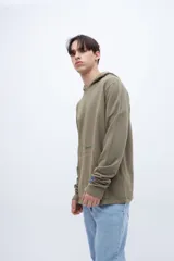 Canguro verde oliva de felpa liviana teñido en prenda, con capucha, bolsillo tipo canguro y puños acanalados. Estampa con la leyenda "UNFRM-STATE" en el pecho y detalle de estampa en la manga. Corte recto.