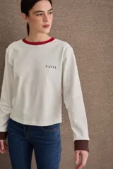 Remera de manga larga color marrón, con cuello en tono verde claro y puños en tono celeste. Presenta el logo de la marca bordado en el pecho.