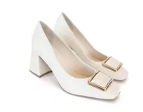 Stiletto de cuero color hueso con punta cuadrada y aplique metálico dorado en el empeine. Tiene un taco ancho de altura media con textura geométrica.