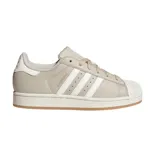 Championes Adidas modelo Superstar, color beige con las icónicas tres tiras laterales en blanco. Presenta la clásica puntera de goma, suela de plataforma blanca y base de goma color caramelo.
