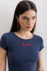 Remera azul marino de algodón con cuello redondo y mangas cortas. Tiene tres corazones rojos bordados en el pecho.