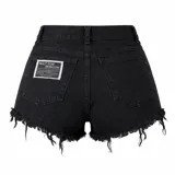 Short de jean negro de tiro alto, con ruedo deshilachado y etiqueta decorativa con texto en el bolsillo trasero.
