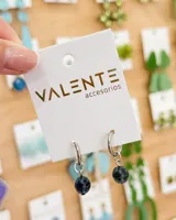 Aros tipo argolla pequeña de acero con un dije colgante de piedra esférica en tono azul oscuro traslúcido.