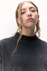 Sweater de lana color crema, de cuello alto y corte holgado.