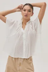 Blusa blanca de algodón con detalle metalizado, cuello con punto smock y mangas raglán.