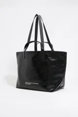 Bolso tipo tote de Bimba y Lola, color dorado con acabado metalizado y efecto arrugado. Presenta un diseño cuadrado con estampado central de la marca en un recuadro oscuro y doble asa de mano en color crema.