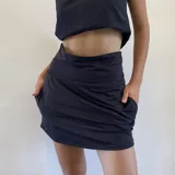 Minifalda negra con short incorporado, de diseño deportivo con cintura ajustable que permite usarla de tiro alto o bajo y bolsillos laterales.