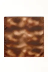 Pañuelo cuadrado de satén con estampado abstracto en tonos rojizos y grises, anudado en la parte inferior.