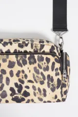 Bolso bandolera Bimba y Lola de tamaño pequeño, confeccionado en nylon con estampado animal print. Presenta estructura blanda, asa regulable de tejido negro, cierre principal con cremallera y bolsillos laterales con cierre.