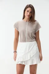 Minifalda blanca envolvente, con diseño cruzado, volados en el borde y detalles de frunces en el lateral.