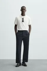 Jersey de punto color verde oliva, de calce relajado (relaxed fit), con cuello solapa y abertura frontal en forma de V. Es de manga corta y presenta acabados en rib en puños y ruedo.