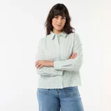 Camisa de manga larga color verde menta con estampado de cuadros vichy y delicado bordado inglés floral. Presenta cuello camisero clásico, cierre frontal abotonado oculto y terminaciones onduladas en el ruedo.