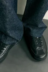 Zapatillas de estilo retro para hombre, de color negro, con diseño monocolor y cordones a tono. Presentan una parte superior con combinación de piezas y suela dentada.