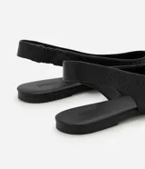 Zapatilla tipo slingback de cuero negro con textura de piel de serpiente, diseño destalonado con tira elástica trasera y punta fina.