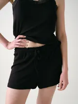 Short negro confeccionado en tejido rib, con cintura elastizada y cordón ajustable.