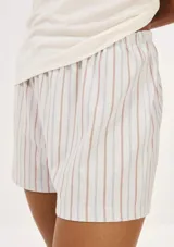 Pijama de algodón compuesto por una remera blanca de manga corta con inscripción frontal y un short a rayas en tonos salmón y beige con cintura elástica.