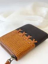 Billetera pequeña de cuero marrón y negro con cierre metálico y monedero interno.