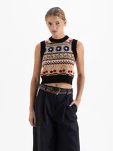 Chaleco tejido de punto con diseño jacquard multicolor que incluye motivos de flores, cerezas y patrones geométricos. Presenta escote redondo, sisas y ruedo con terminación en rib negro, con un corte corto al cuerpo.