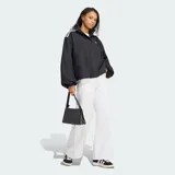 Campera Adidas de corte amplio tipo blouson, color negro con sutil patrón a cuadros. Presenta cuello alto, hombros caídos, mangas voluminosas con puños elastizados y las clásicas tres tiras blancas en los hombros. Incluye el logo del trifolio bordado en el pecho.