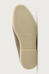 Mocasín destalonado de hombre fabricado en piel con acabado en gamuza, color marrón claro, con detalle de bordón en la parte superior, horma redonda y suela plana a contraste.