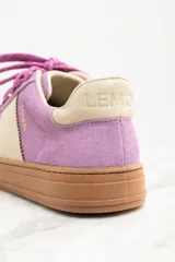 Zapatilla urbana de gamuza color lila con detalles en beige y suela marrón.