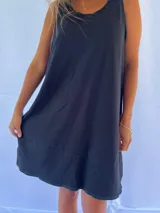 Vestido playero de corte holgado y diseño minimalista, confeccionado en algodón. Presenta cuello redondo, sisas amplias y aberturas laterales en el ruedo con pespuntes en contraste.