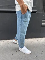 Pantalón de jean estilo slouchy, con corte holgado en la parte superior y ajuste hacia los tobillos. Presenta un lavado azul claro clásico y diseño de cinco bolsillos.